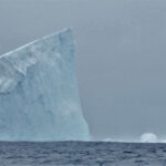 Antarctica iceberg floating in the ocean on a cloudy day, highlighting the majestic beauty of polar landscapes.